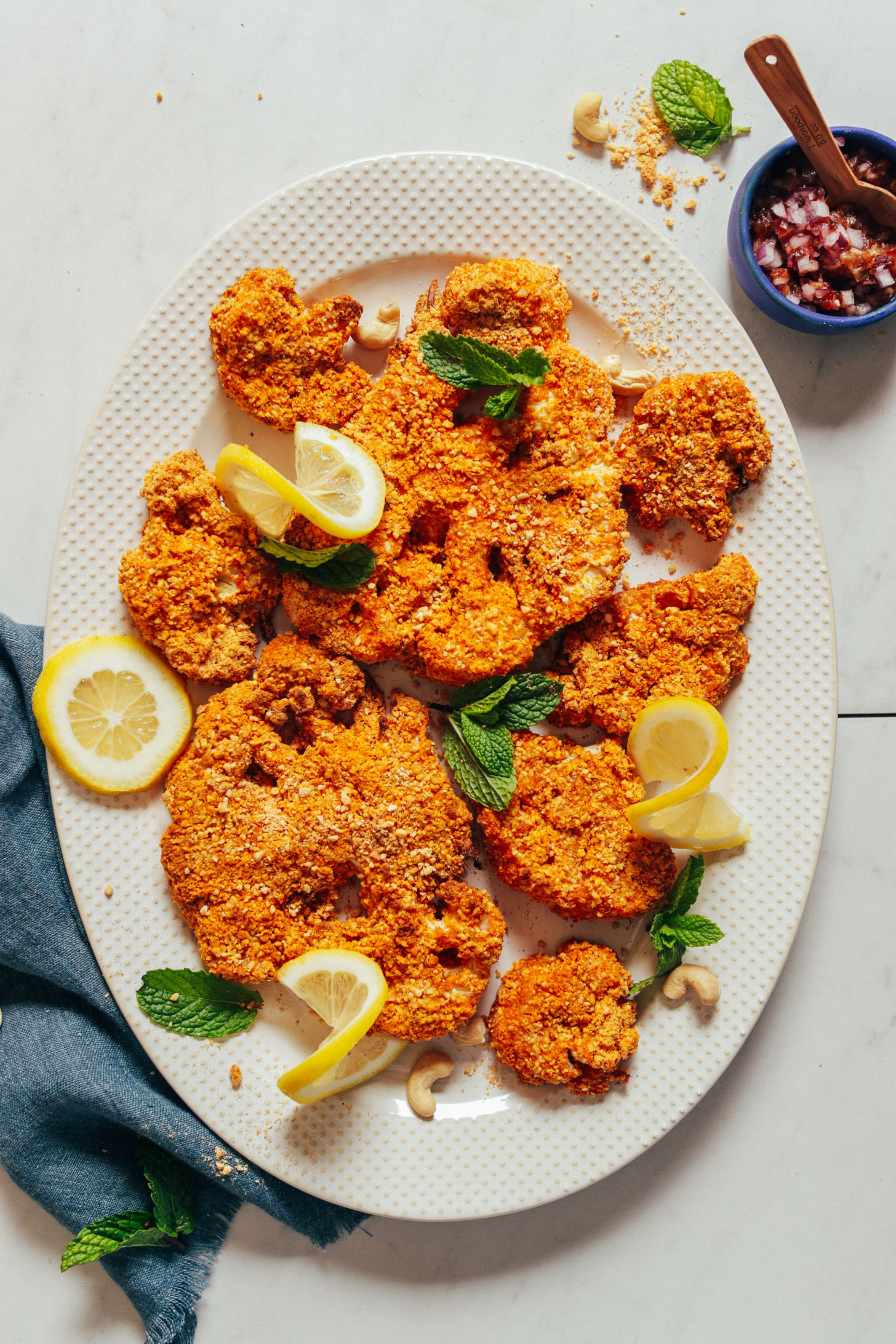 Platter of Cashew Crusted Cauliflower Steaks with lemon, mint, and a red onion date relish