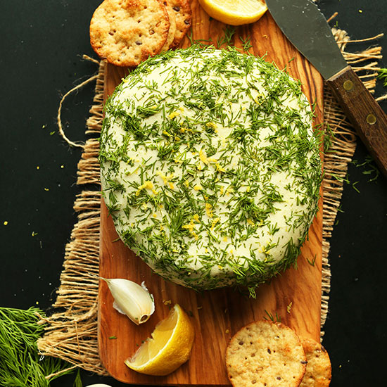 Dill Garlic Vegan Cheese Wheel on a wood cutting board with crackers